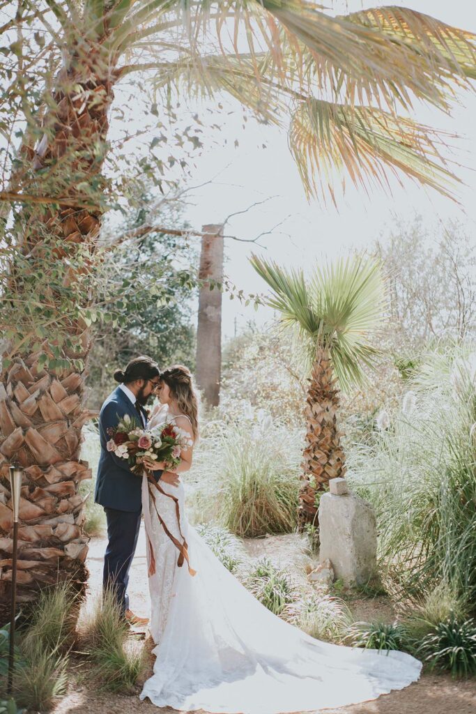 A newly married couple poses for a photo in front of palm trees